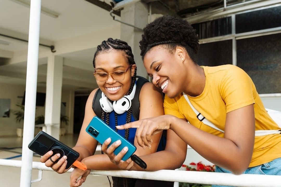 Two friends share a smartphone while standing together outdoors
