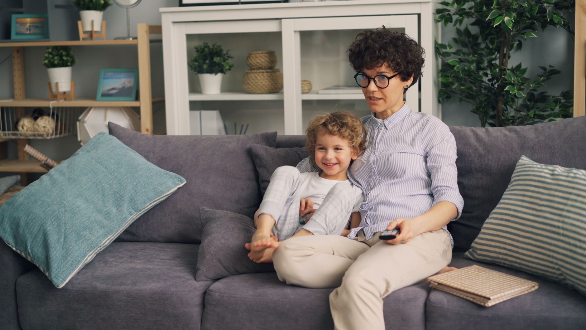 Parent and child sharing a sofa while holding a remote control