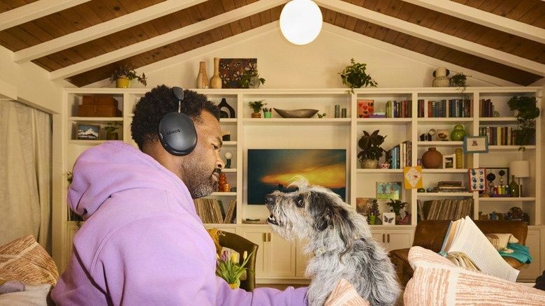 Person wearing over-ear headphones beside a dog in a home
