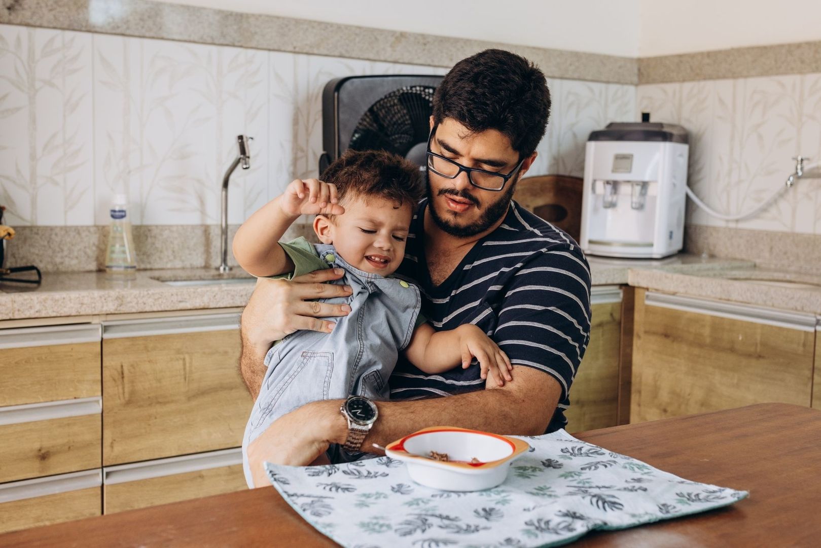 Parent holding a young child during a casual kitchen meal