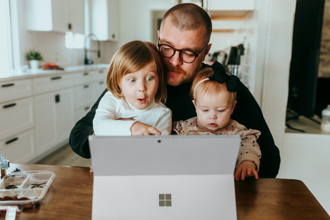 Parent and two children looking at a tablet together at a kitchen table